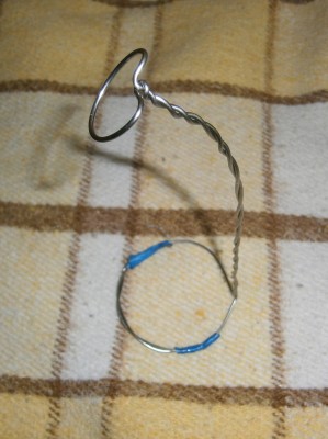 Stainless steel welding rod, twisted and bent into shape. It's plenty rigid for the task.